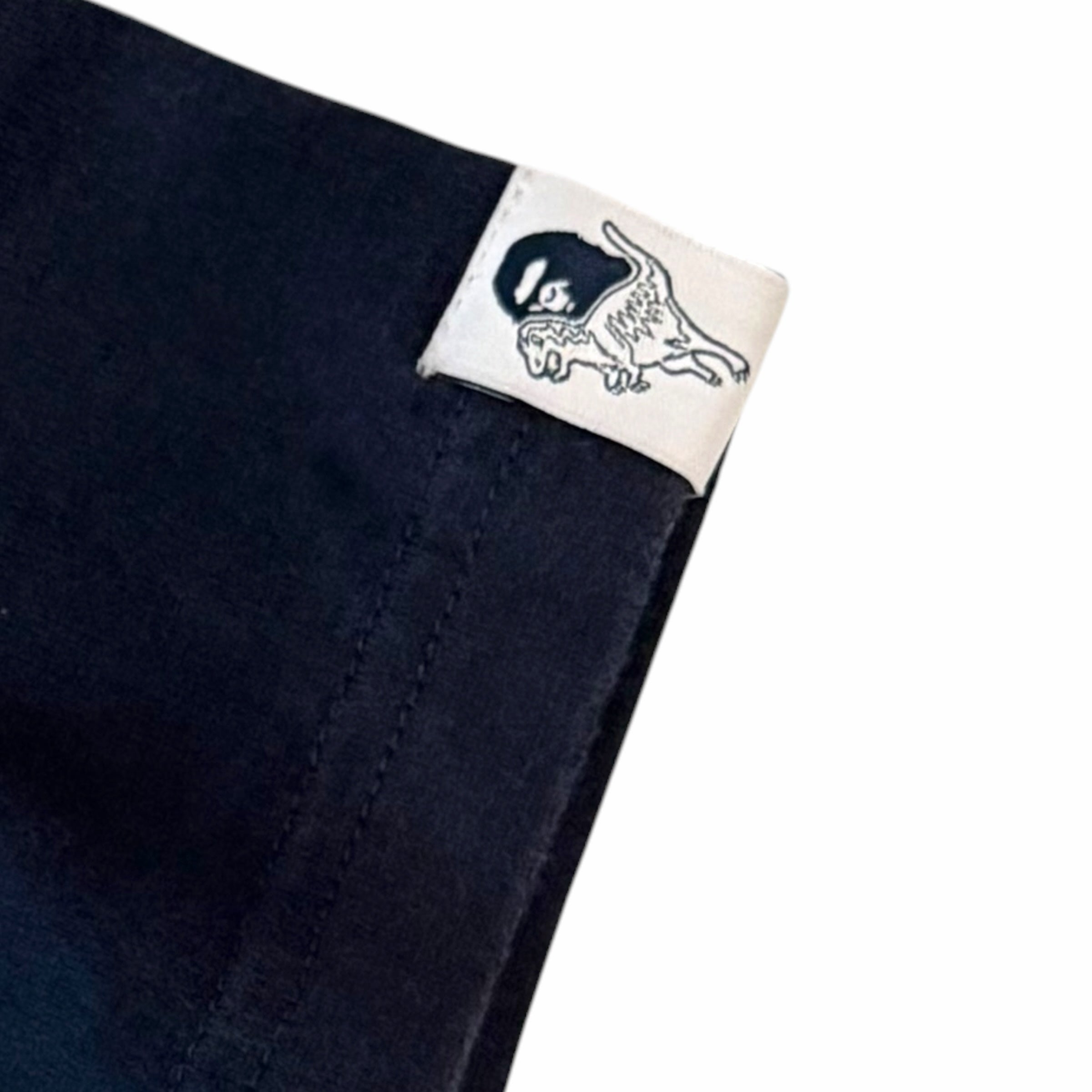 Vangsworld, Inc navy blue cotton t-shirt sleeve featuring a white collaborative BAPE x Coach dinosaur logo tab