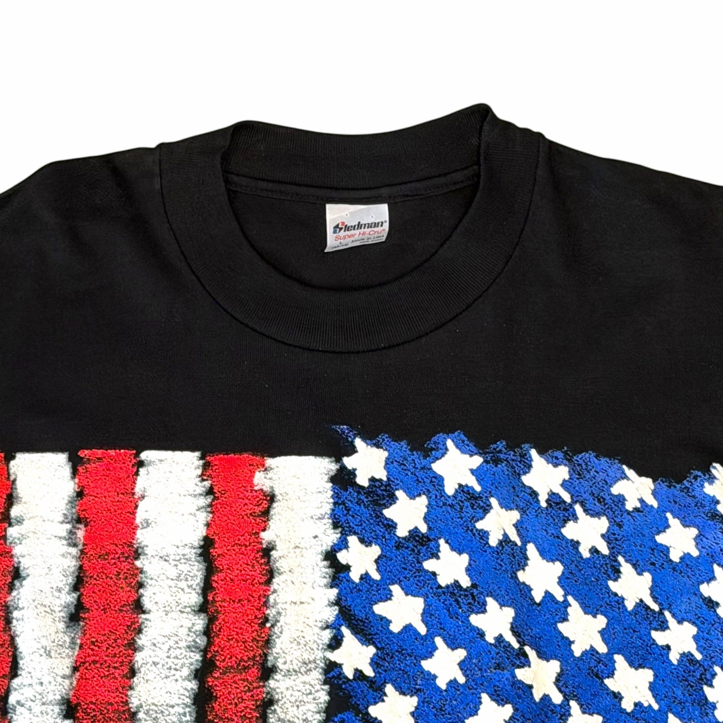 Vangsworld, Inc black crewneck t-shirt featuring a textured red, white, and blue American flag brushstroke graphic.