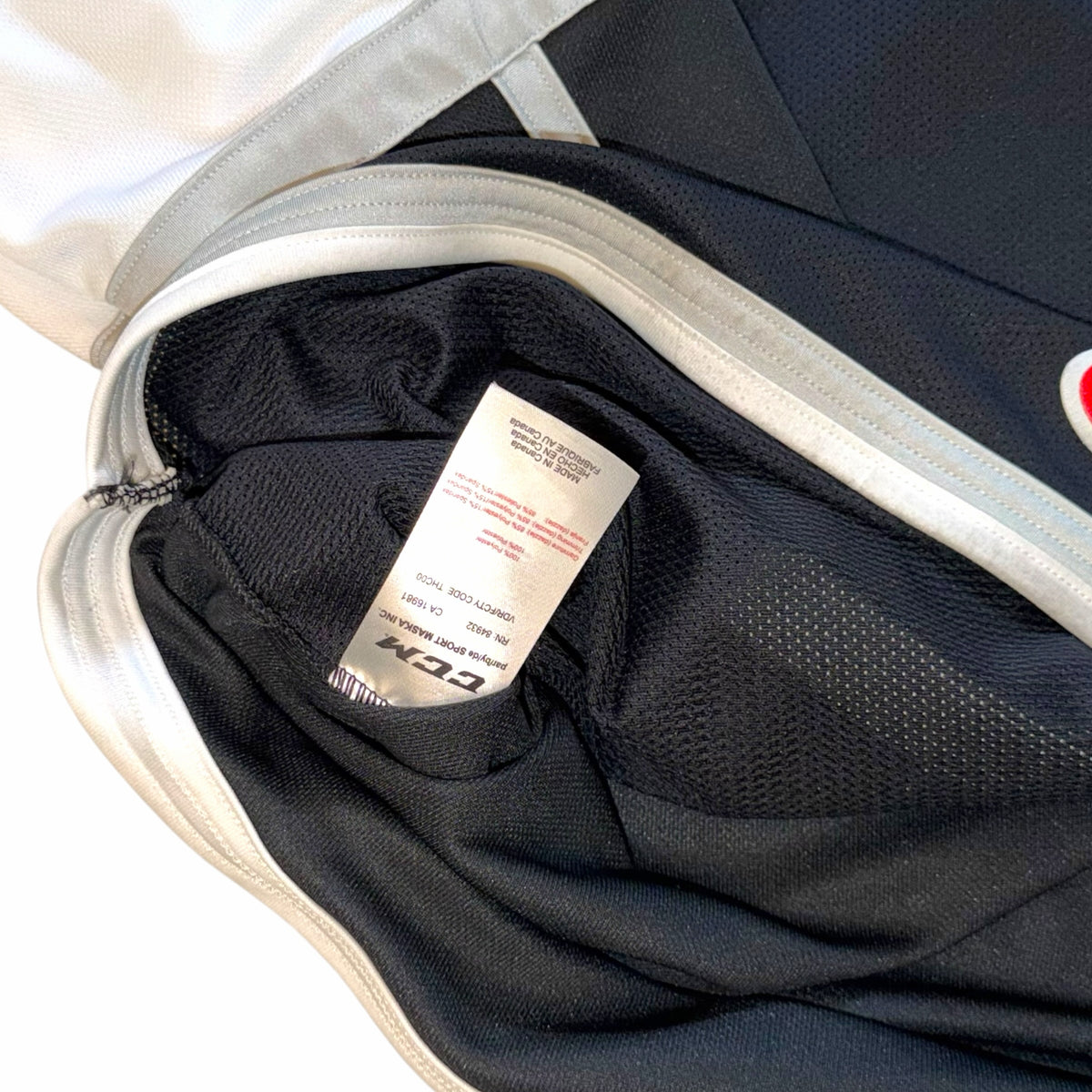 Vangsworld, Inc Ontario Reign hockey jersey interior showing CCM brand label and fabric care tag on black mesh