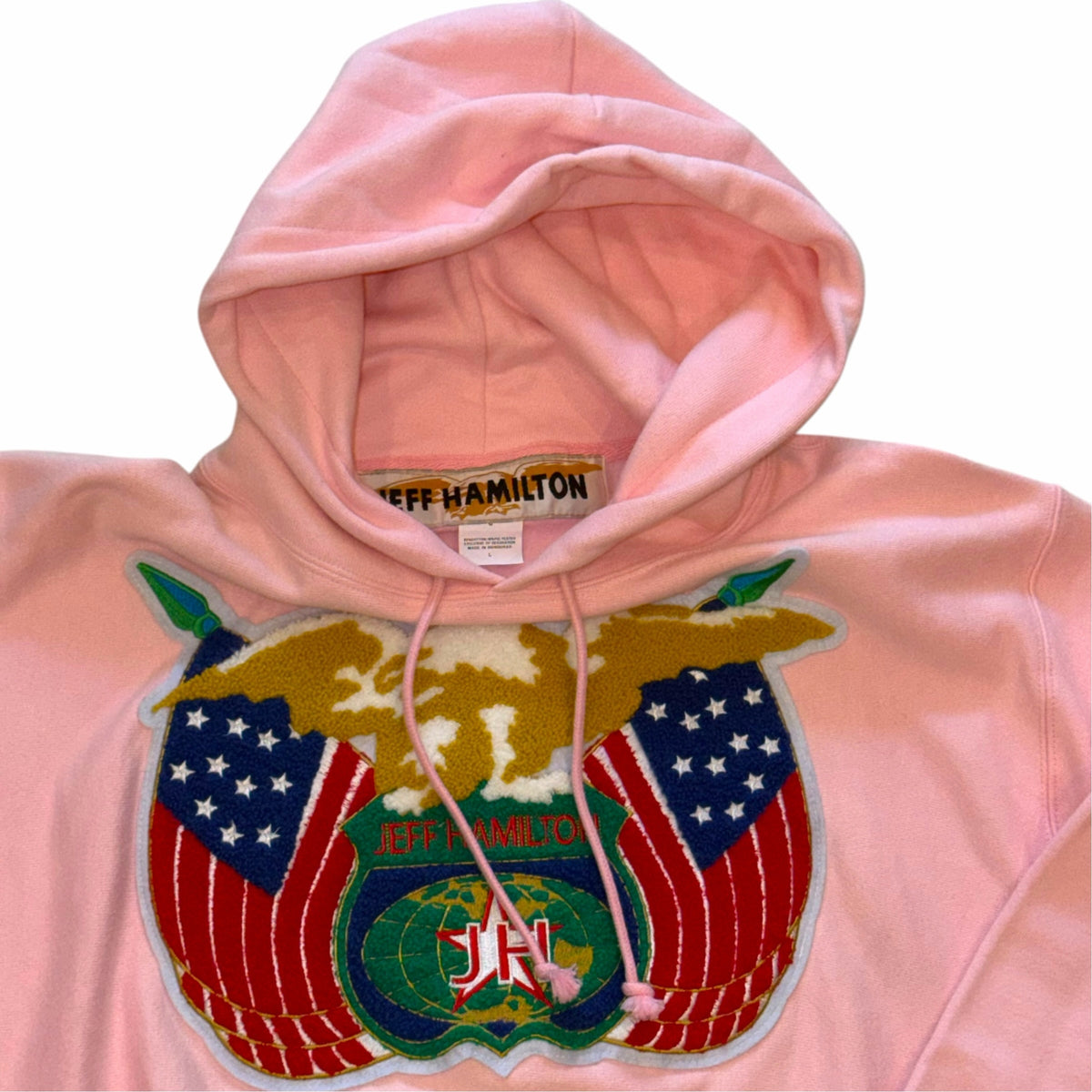 Vangsworld, Inc pastel pink Jeff Hamilton hooded sweatshirt with a large eagle and American flag embroidered patch.