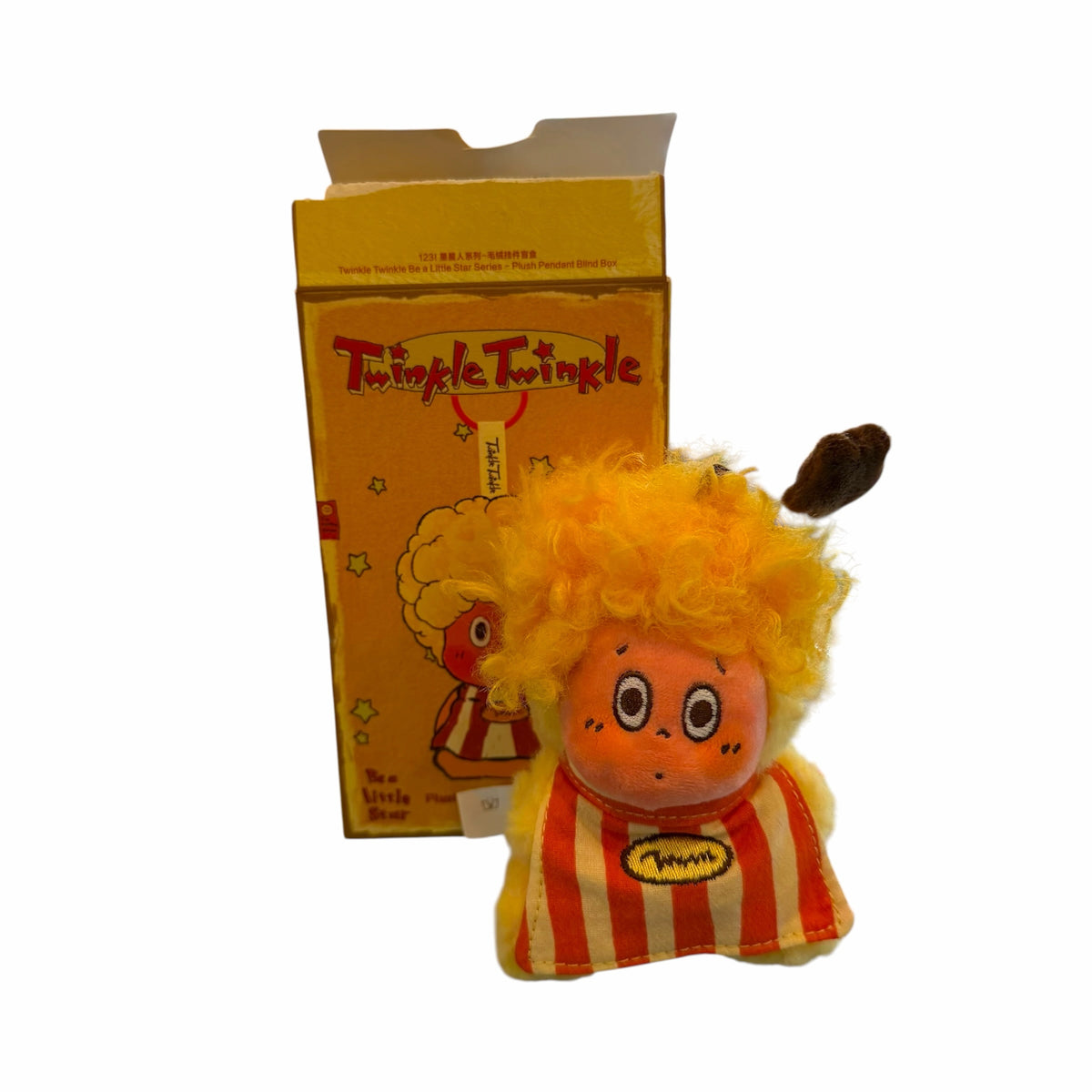Vangsworld, Inc Twinkle Twinkle plush pendant with yellow hair and striped outfit standing in front of its box.